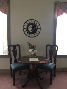 a dining room table with two chairs and a clock on the wall at Oak Valley Inn and Suites in Geneseo