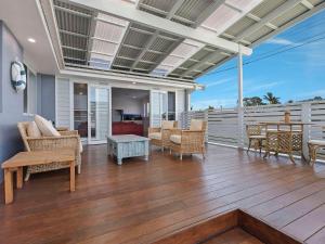 un porche con sillas y una mesa en una terraza en Blue Summer House en Long Jetty