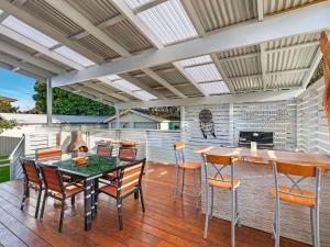 un patio con mesa, sillas y chimenea en Blue Summer House en Long Jetty