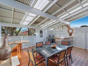 un patio con mesa y sillas en una terraza en Blue Summer House en Long Jetty
