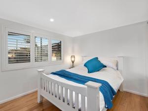 Un dormitorio blanco con una cama blanca y una ventana en Blue Summer House en Long Jetty