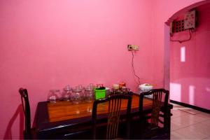 a dining room with a pink wall and a wooden table at RedDoorz Syariah near Telaga Warna Dieng in Diyeng