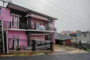 a pink building with a fence in front of it at RedDoorz Syariah near Telaga Warna Dieng in Diyeng