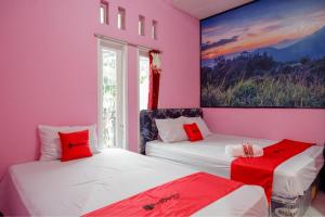 two beds in a room with pink walls at RedDoorz Syariah near Telaga Warna Dieng in Diyeng