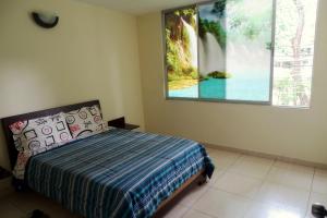 a bedroom with a bed and a large window at APARTAESTUDIOS AMOBLADOS ARBOLEDA DE CADIZ in Ibagué