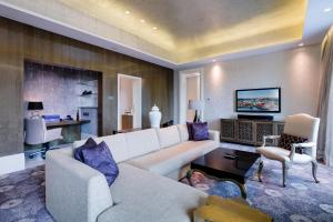 a living room with a white couch and a tv at Resorts World Sentosa - Hotel Michael in Singapore +38 photos