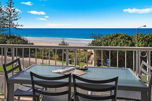 d'une table et de chaises sur un balcon avec vue sur la plage. dans l'établissement Grand Palais Beachside Resort, à Alexandra Headland