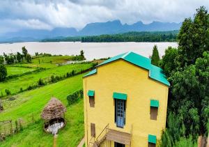 ein gelbes Haus mit blauem Dach auf einem grünen Feld in der Unterkunft The Satpura Panchtatva Villa in Khāpa