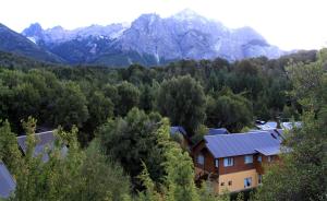 a house in a forest with mountains in the background at Cabañas Tierra Sureña in San Carlos de Bariloche