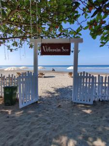 ein Schild am Strand mit zwei weißen Stühlen in der Unterkunft Buena Vida Beach Resort in Morjim