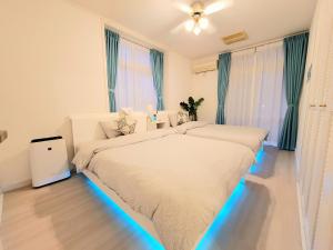 two beds in a bedroom with blue lights at Villa Blu Okinawa Chatan 2-1 ヴィラブルー沖縄北谷2-1 "沖縄アリーナ徒歩圏内の民泊ホテル" in Chatan