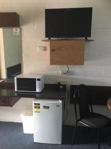 a room with a desk with a television and a chair at Peppercorn motor inn in Narromine