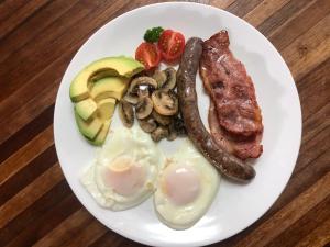 a plate of breakfast food with eggs sausage and mushrooms at Kliprand Guest House in Springbok