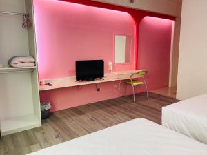 a room with a pink wall with a desk with a television at Han Xiang Ju in Magong