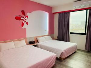 una habitación de hotel con 2 camas y una flor en la pared en Han Xiang Ju, en Magong
