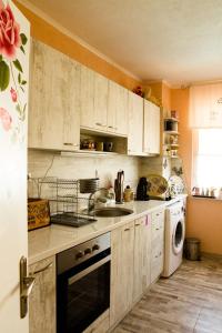 a kitchen with white cabinets and a sink and a dishwasher at Апартамент Fleur in Nesebar