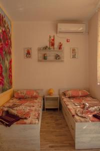a bedroom with two beds and a table and a painting at Апартамент Fleur in Nesebar