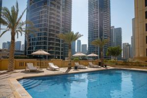 a swimming pool with chairs and umbrellas in a city at Suha JBR Hotel Apartments in Dubai
