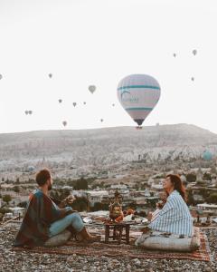 un uomo e una donna seduti a un tavolo con una mongolfiera di Kelebek Special Cave Hotel & Spa a Göreme