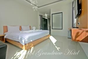 a bedroom with a bed with white sheets and a mirror at Saichon Grand View in Ban Lam Rua Taek