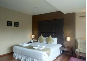 a bedroom with a large white bed with a large headboard at Grand Gardenia in Tiruchirappalli