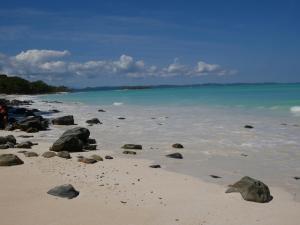 a beach with rocks on the sand and the water w obiekcie Le Zahir de l'ile - Iranja na Nosy Be