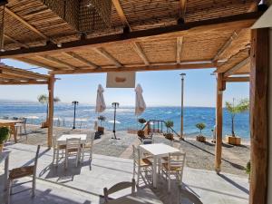 a view of the beach from a restaurant with tables and chairs at Skinosummer in Paralia Agias Foteinis