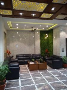 a lobby with black leather couches and plants at Hotel Corbett Kingdom in Rāmnagar