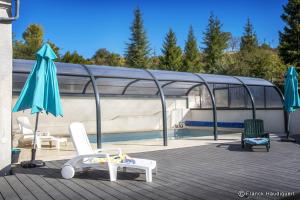 une terrasse avec 2 chaises, un parasol et une piscine dans l'établissement Gite Domaine de Trevety, à Châtillon-sur-Cher