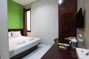 a room with a bed and a sink and a television at LeGreen Suite Setiabudi in Jakarta