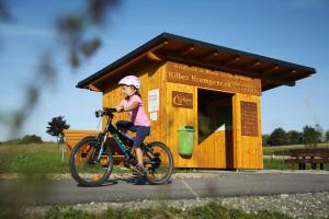 Naturfreunde Alpenvorland في Kilb: فتاة صغيرة تركب دراجة أمام المبنى