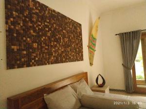 uma sala de estar com um sofá e uma prancha de surf na parede em Harris surf villa em Pulukan