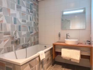 a bathroom with a tub and a sink and a mirror at Fletcher Hotel-Restaurant Scheveningen in Scheveningen