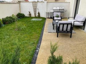 a backyard with a lawn with chairs and a grill at Appart près de Meaux in Chambry