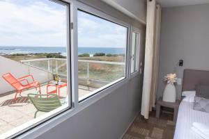 een slaapkamer met een balkon met uitzicht op de oceaan bij Hôtel Le Lichen De La Mer in Batz-sur-Mer