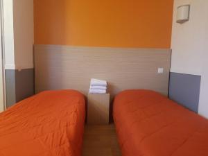 2 camas en una habitación pequeña con sábanas de color naranja en HECO Colmar Nord - ex Première Classe en Houssen