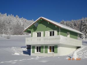 una casa verde y blanca en la nieve en La Bresse Hautes Vosges Chalet le Paiquis, en La Bresse