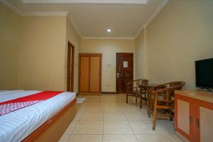1 dormitorio con 1 cama, mesa y sillas en OYO 1273 Hotel Belvena, en Palembang