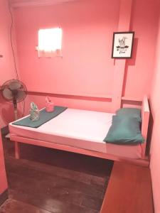 a bed in a room with a pink wall at Ken's Inn in Coron