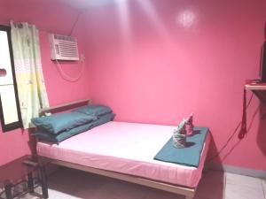 een kamer met een roze muur met een bed erin bij Ken's Inn in Coron
