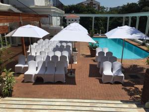 a group of white chairs and umbrellas next to a pool at Emakhosini Boutique Hotel in Durban
