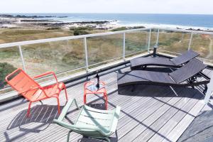 two chairs and a table on a deck with the beach at Hôtel Le Lichen De La Mer in Batz-sur-Mer