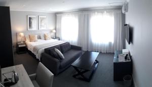 a bedroom with a bed and a couch and a window at Villa Tuscana in Port Elizabeth