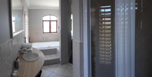 a bathroom with a sink and a bath tub at Villa Tuscana in Port Elizabeth