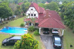 a house with cars parked in front of a swimming pool at Villa Mommy A Famosa Resort in Melaka