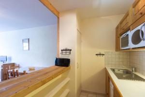 a kitchen with a counter with a sink and a microwave at Vacancéole - Résidence Le Sappey - Les 2 Alpes in Les Deux Alpes +7 photos