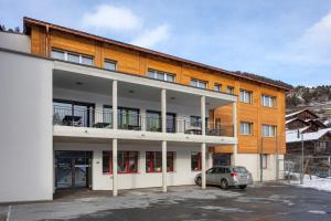 a building with a car parked in a parking lot at Hotel Roggen in Erschmatt