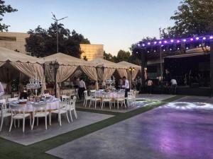 a group of tables and chairs under tents with lights at City Palace Hotel Tashkent in Tashkent