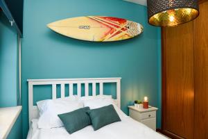 a bedroom with a blue wall with a surfboard on the wall at Villa Pedras Muitas - Baleal in Baleal