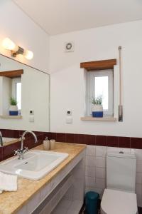 Un baño con lavabo e inodoro y dos ventanas. en Villa Pedras Muitas - Baleal, en Baleal
